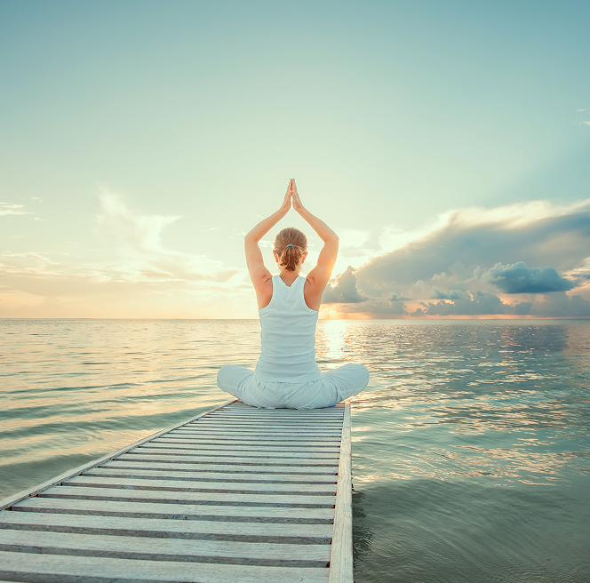 Woman practicing yoga and meditation at sunrise, reflecting Ayurvedic lifestyle guidance and Dinacharya routine in Perth